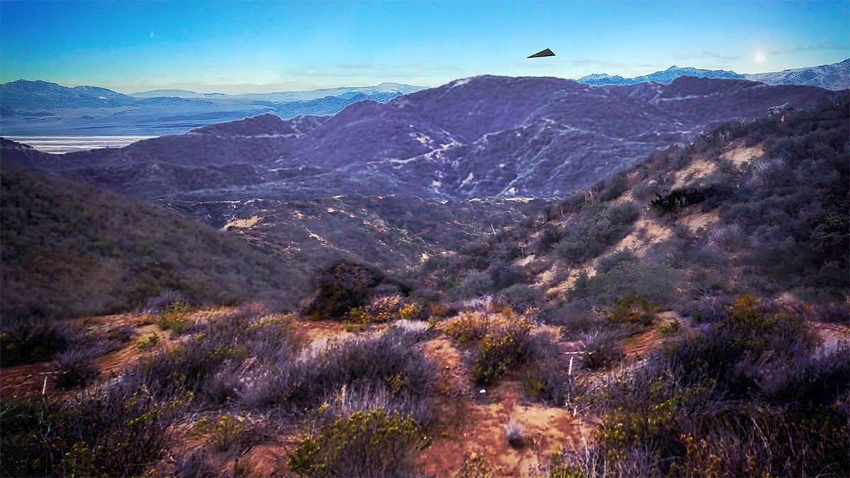 An image released with a 2026 FBI report depicts a black triangular object above mountainous terrain. Federal agents reported seeing a silent, triangular object hover above a ridgeline before accelerating into a canyon. Authorities have not confirmed whether the image is an actual photograph or a reconstruction. (Department of War)
